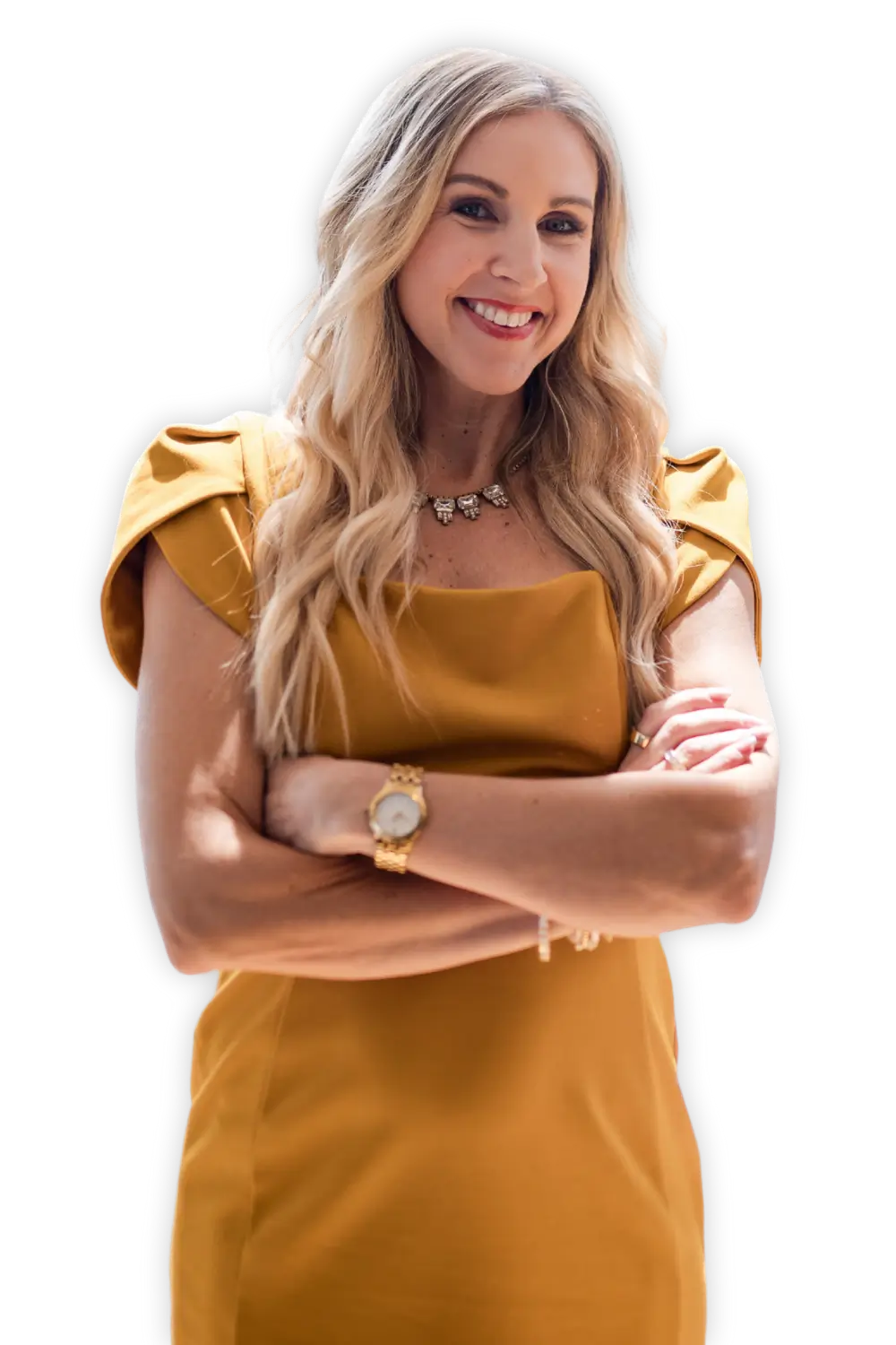 Stacy Tuschl with long blonde hair, wearing a mustard yellow dress and gold jewelry, stands with arms crossed and smiles confidently against a black background, embodying the spirit of Well-Oiled Operations®.